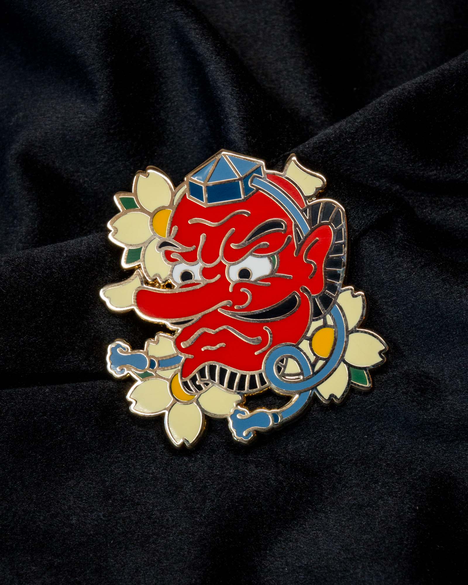 Tengu enamel pin from the Immovable collection by Geoffrey Wong, featuring a red mountain spirit mask that embodies protection, pride, and discipline.