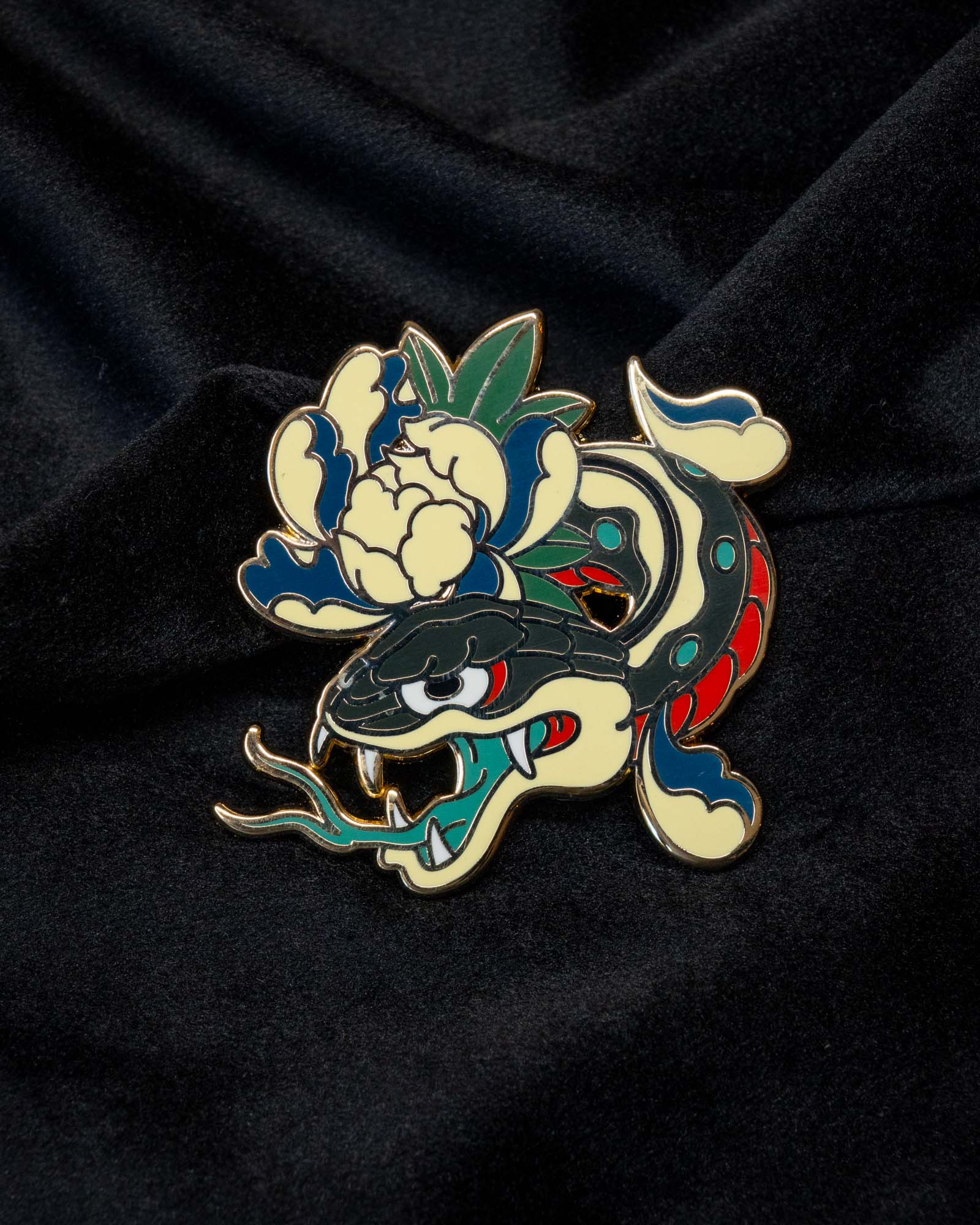 Snake and Peony enamel pin from the Immovable collection by Geoffrey Wong, showing a coiled serpent intertwined with a peony flower symbolizing balance between strength and beauty.