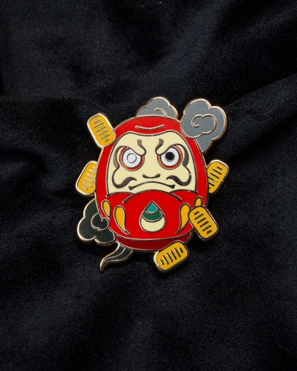 Daruma enamel pin from the Immovable collection by Geoffrey Wong, featuring a red Daruma design symbolizing perseverance, luck, and determination.