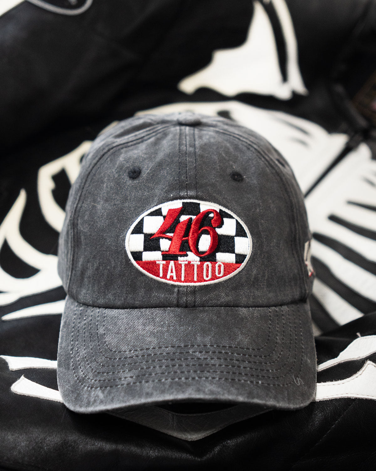 Black cap with a red and white "46 tattoo" logo on a black and white patterned background
