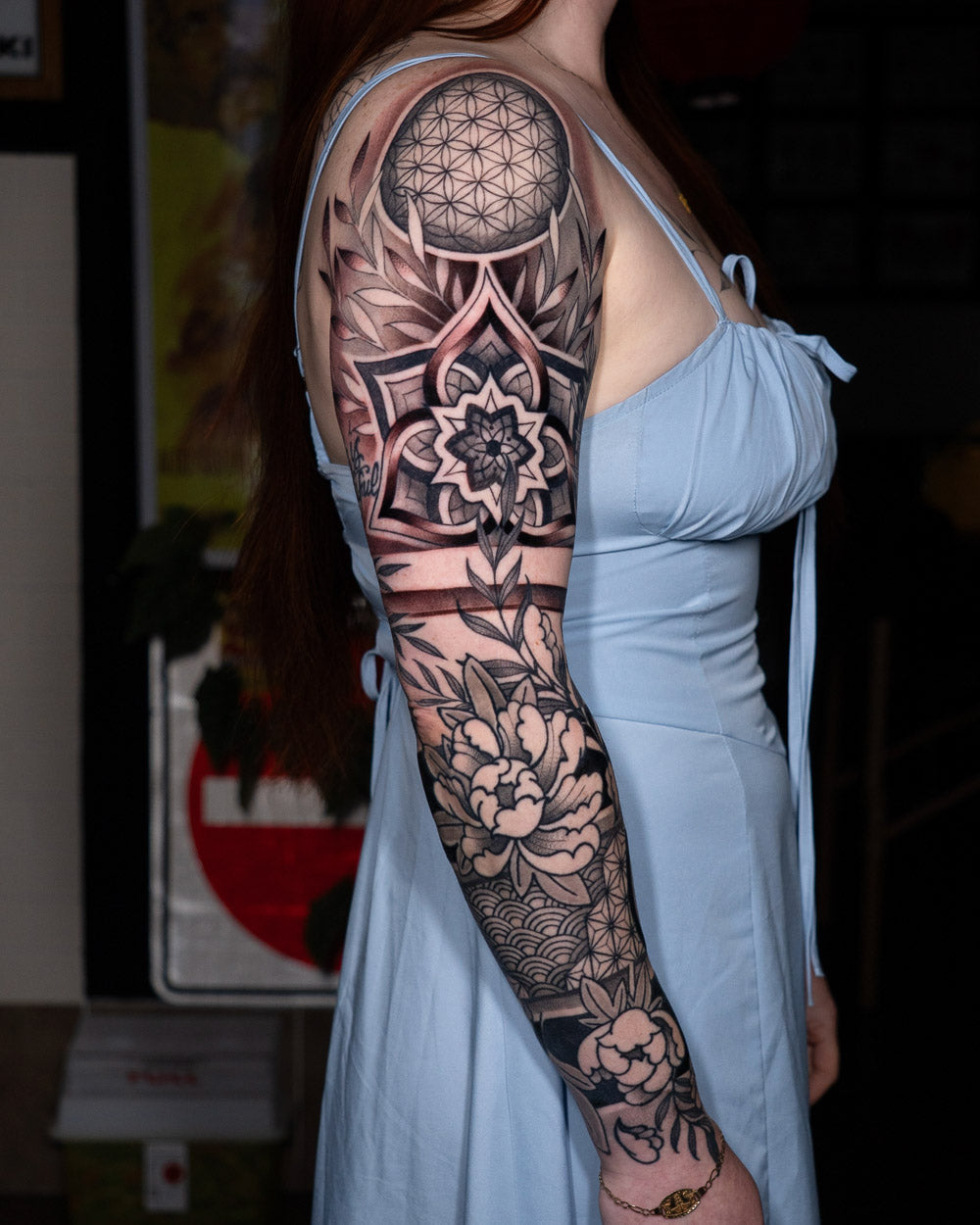 Black and grey ornamental floral and geometric sleeve tattoo with mandala and sacred geometry patterns on the upper arm